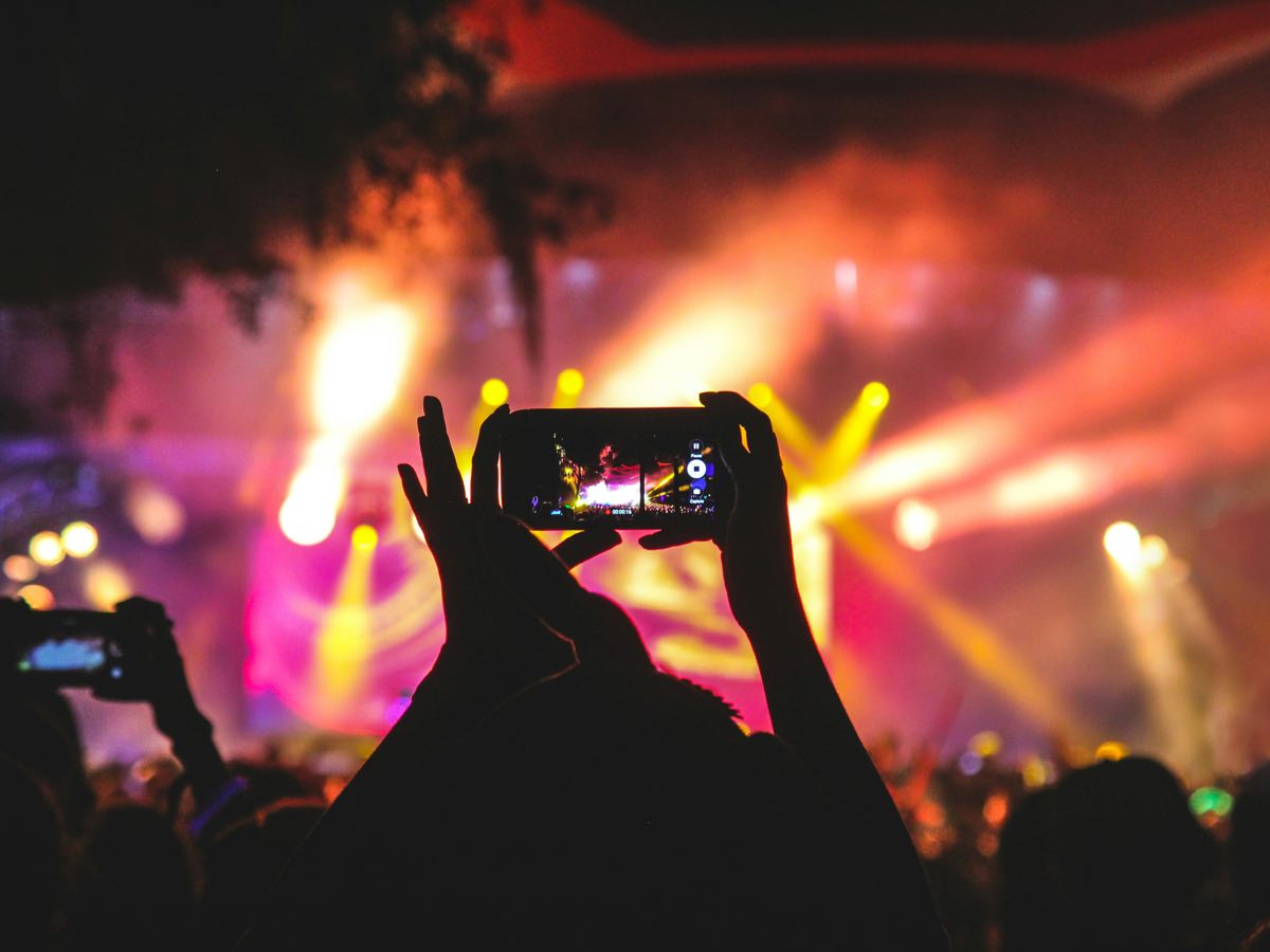 Publikum filmt ein Open-Air-Konzert mit farbigen Scheinwerfern und Nebel