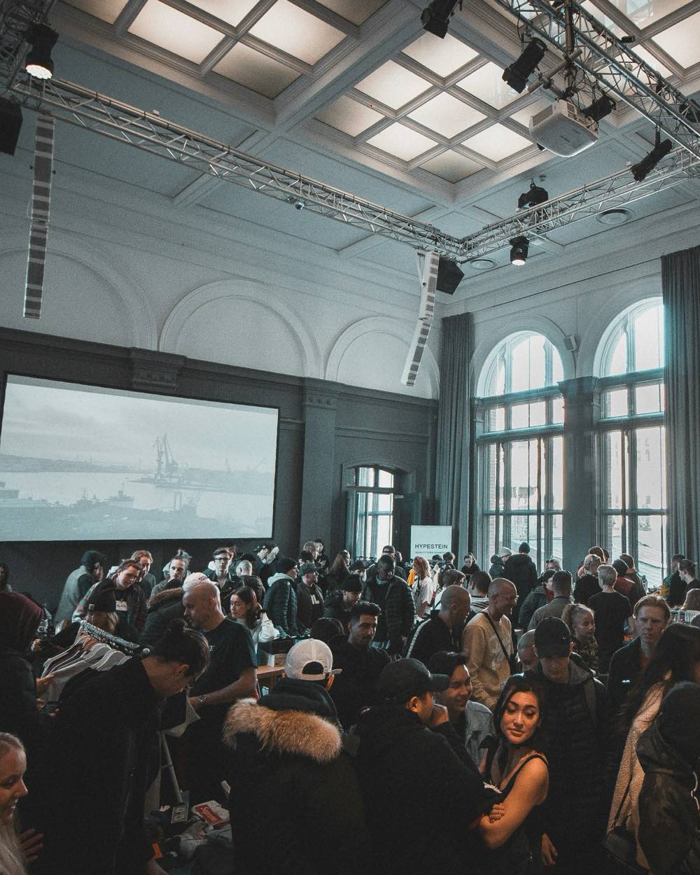 Veranstaltung im Saal mit Traversen, Scheinwerfern, Line-Array-Lautsprechern und Projektionsleinwand